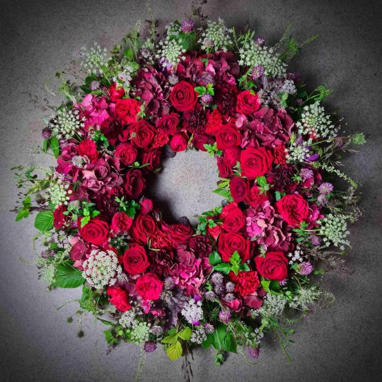 begravningskrans med röda rosor och ängsblommor