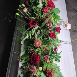 Kistdekoration med röda rosor och skogsinslag